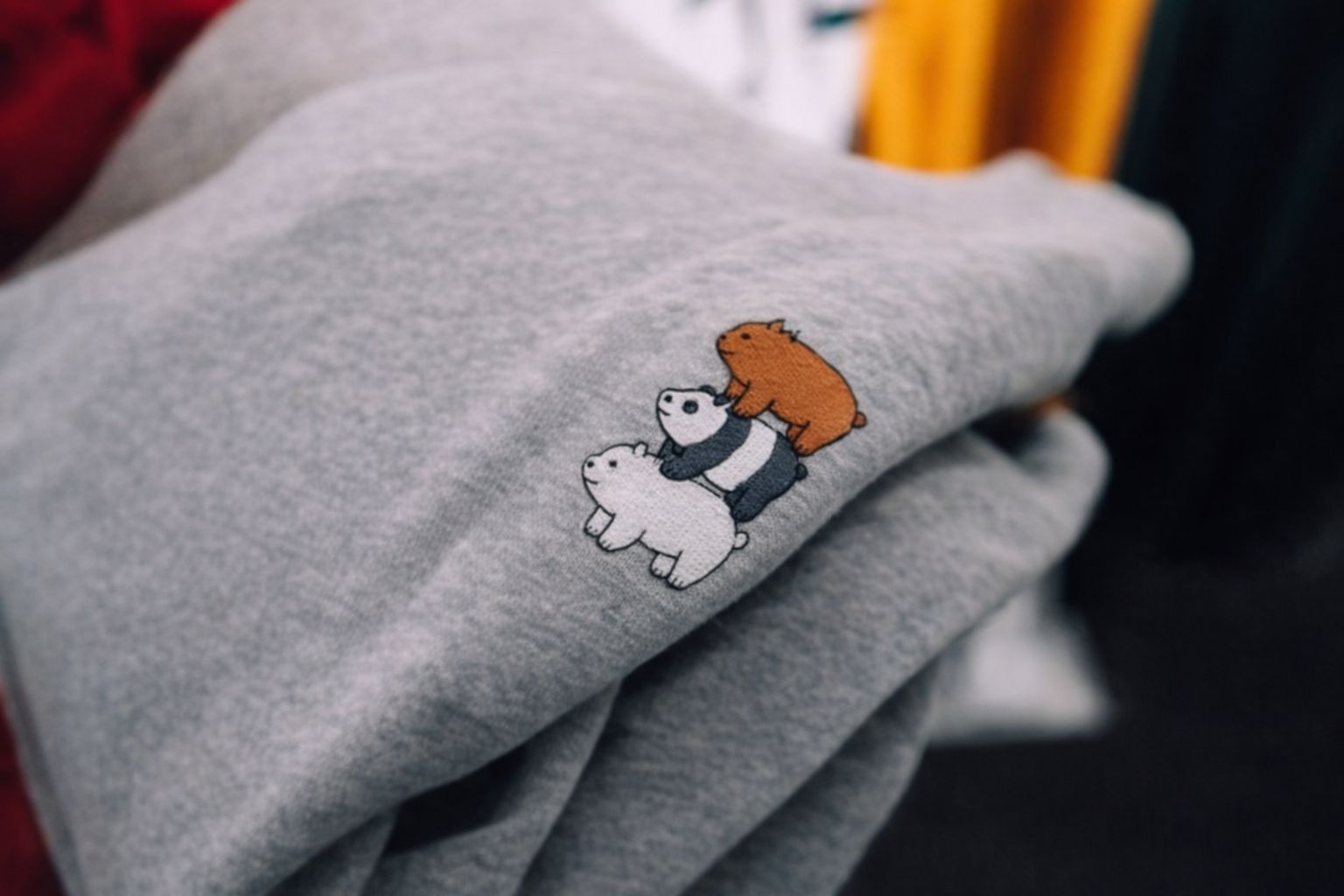 Grå hoodie med broderat tryck av tre björnar staplade på varandra.
